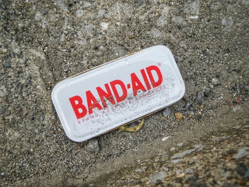 somewhat dirty band-aid container on a cement background